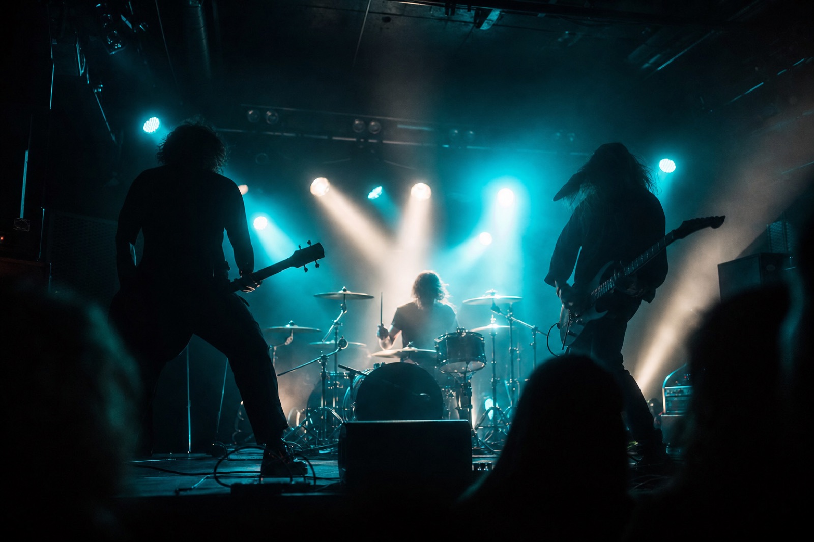 Band rock in controluce su un piccolo palco da club sotto un controluce ciano
